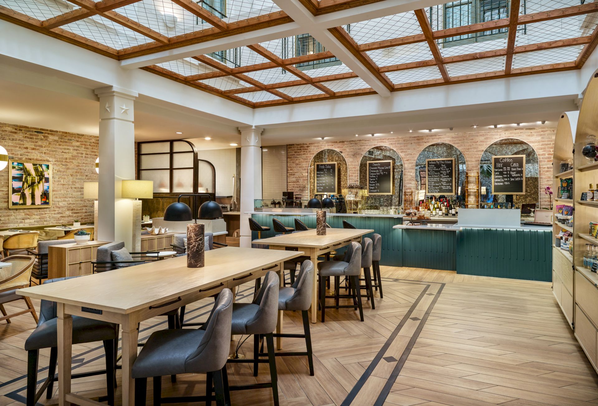 A well-lit cafe with wooden tables, cushioned chairs, a counter with chalkboard menus, and a modern, cozy atmosphere.