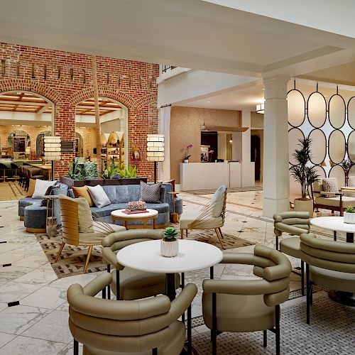 The image shows a modern, stylish hotel lobby with comfortable seating areas, contemporary decor, and a reception desk in the background.